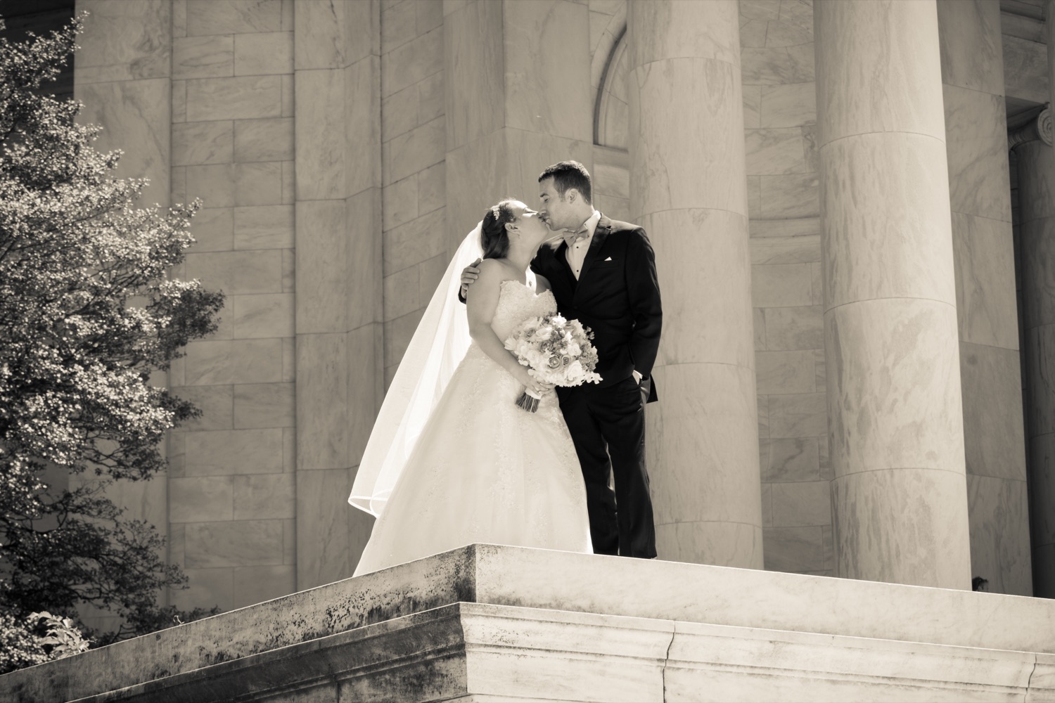 Newlyweds kissing beside marble columns in Washington, DC
